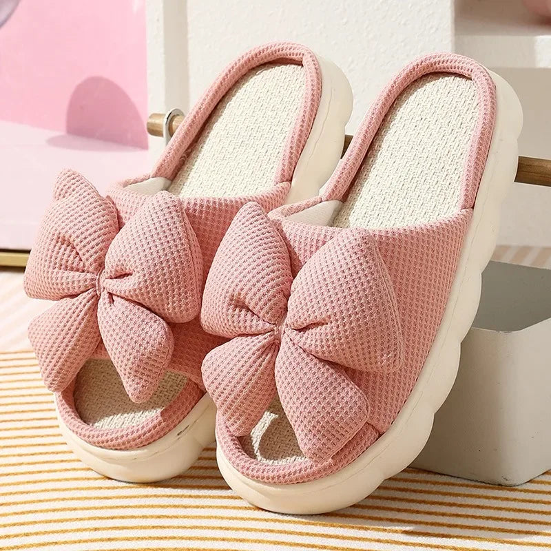 Pink slippers with a large kawaii bow on a striped surface