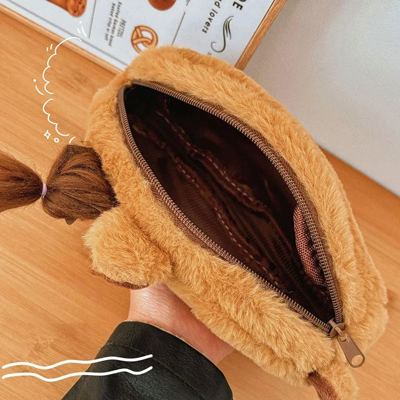 Close-up of a fluffy brown kawaii pouch held by a hand on a wooden surface.