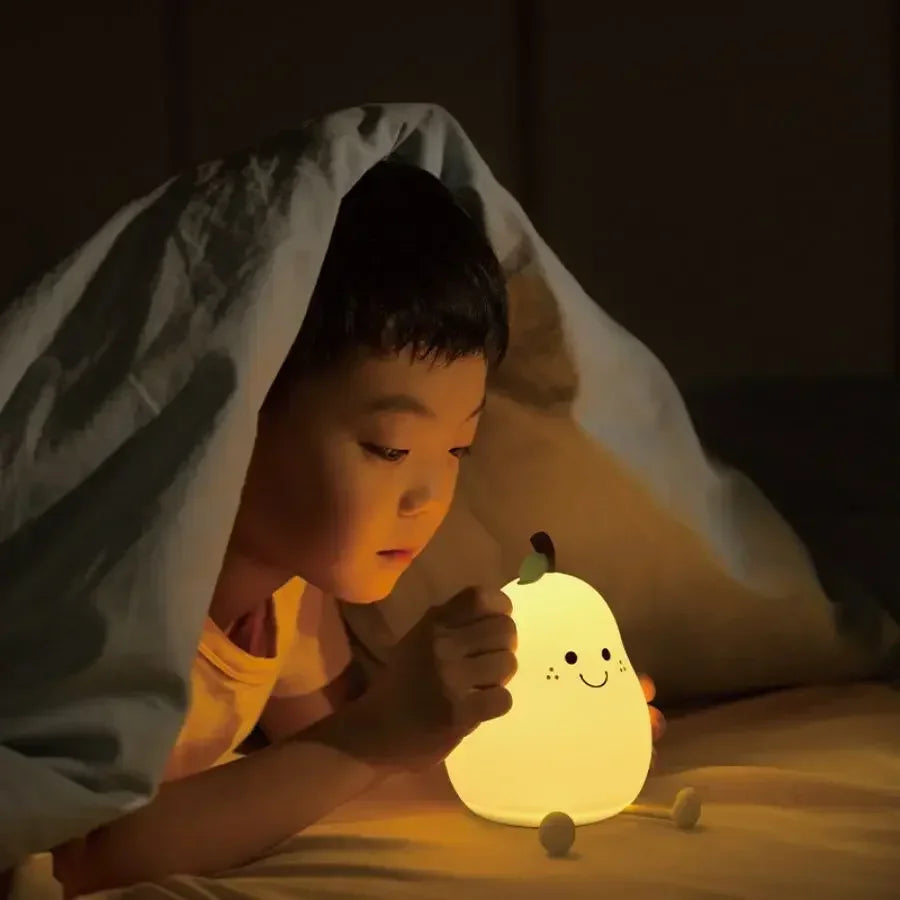 Child holding a glowing kawaii night light under a blanket in a dimly lit room