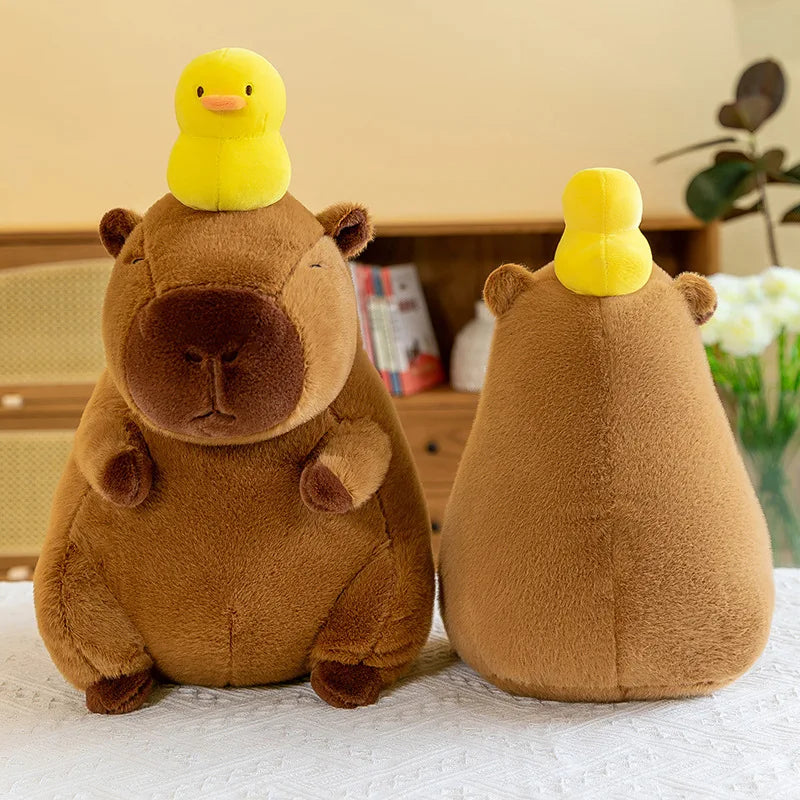 Two kawaii plush toys resembling a bear and a duck with a yellow duck on top of each bear's head, placed on a surface.