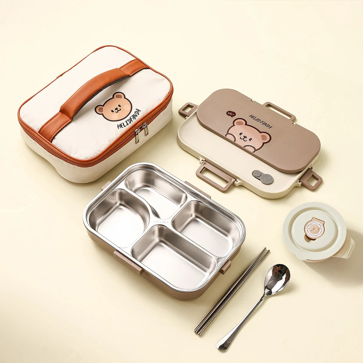Kawaii bear-themed lunch box set with compartments, lid, spoon, and fork on a beige background