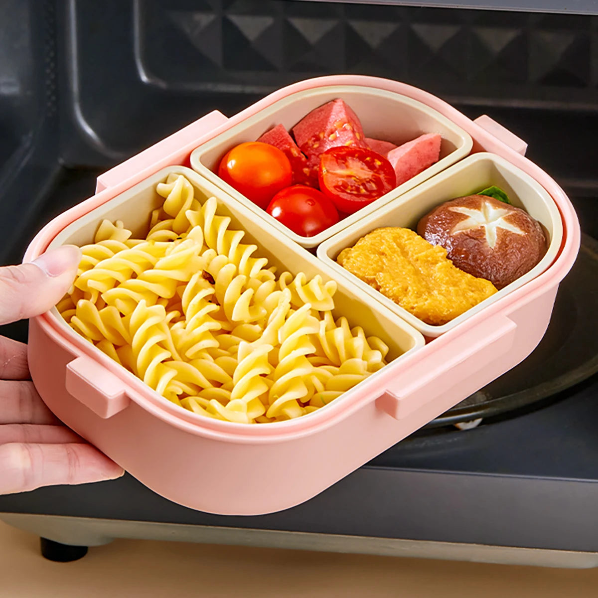Pink kawaii bento box with compartments containing pasta, tomatoes, and other food items.