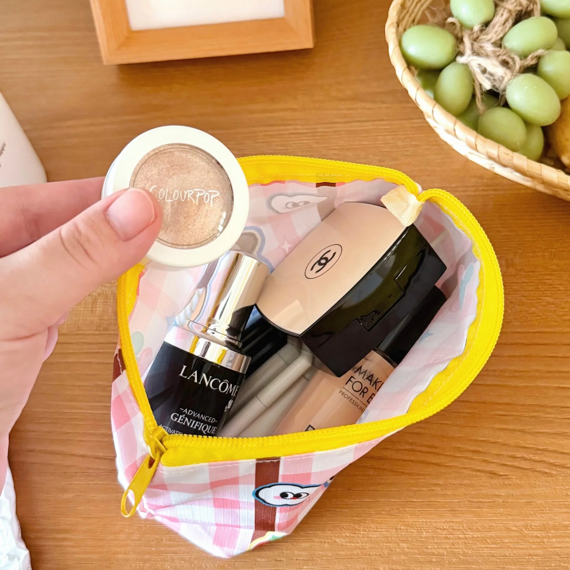 Small Kawaii checkered pouch with makeup items including a product on a wooden surface.