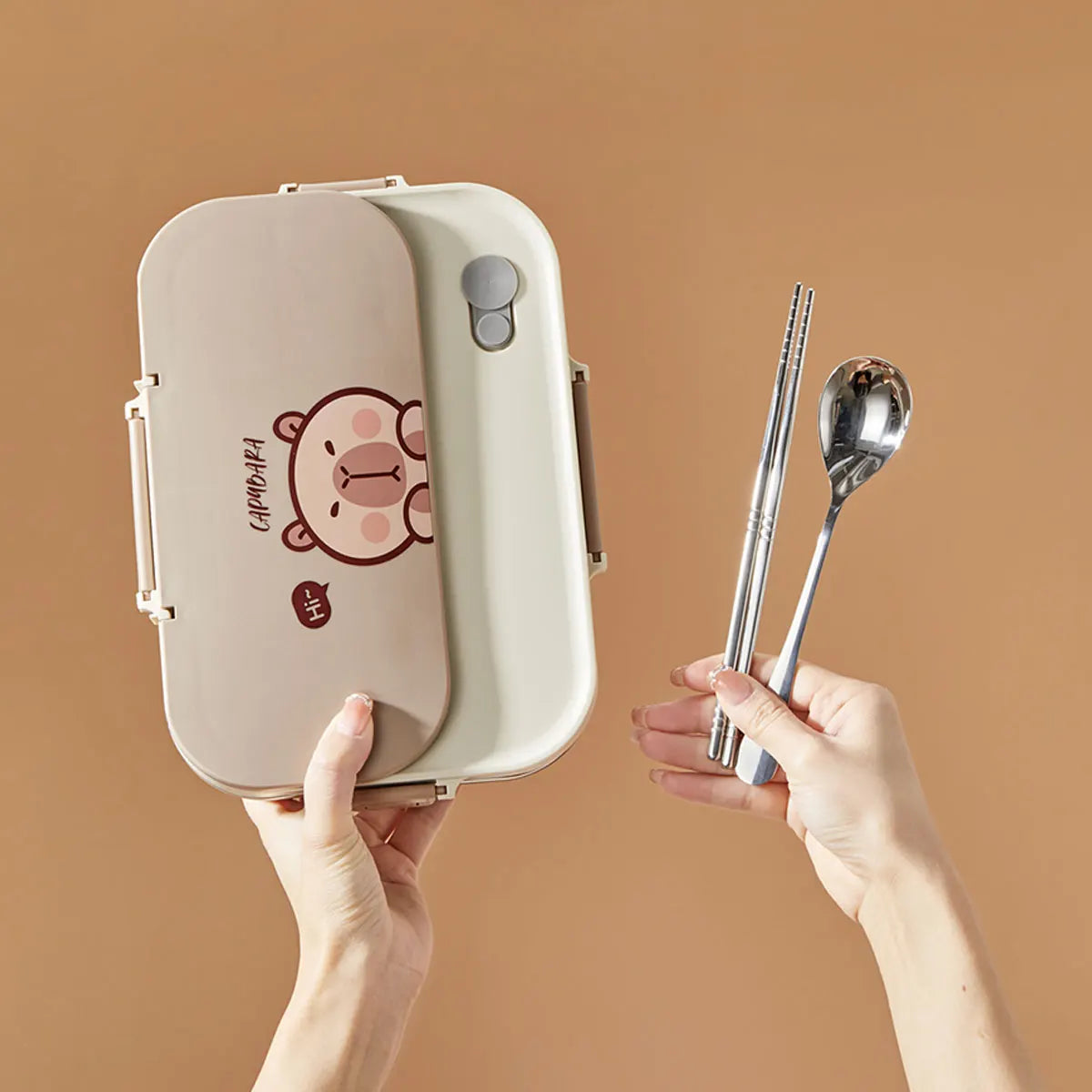 Lunch box with kawaii cartoon design and silver cutlery on a brown background
