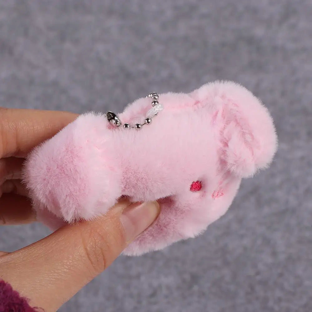 Pink fluffy kawaii keychain held by a hand against a gray background