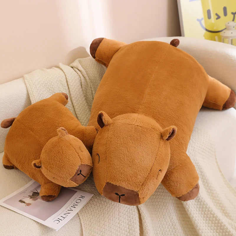 Two brown teddy bear kawaii plush toys on a couch with a magazine underneath.
