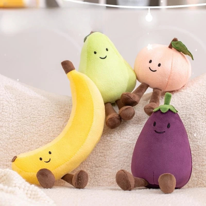 Kawaii plush toys shaped like a banana, avocado, onion, and eggplant on a soft surface.