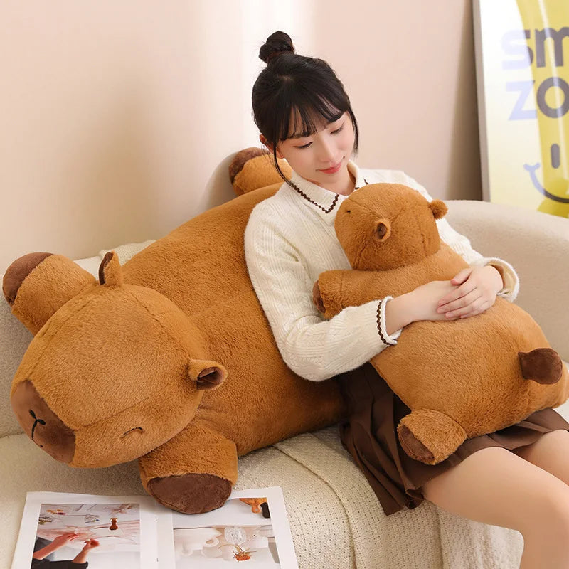 Woman sitting on a couch with a large brown kawaii teddy bear and a smaller one in her arms.