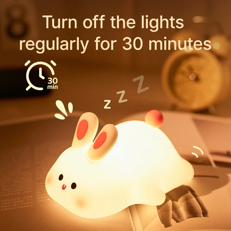 Cute kawaii rabbit-shaped night light with text on turning off lights regularly for 30 minutes, set against a blurred bedroom background.