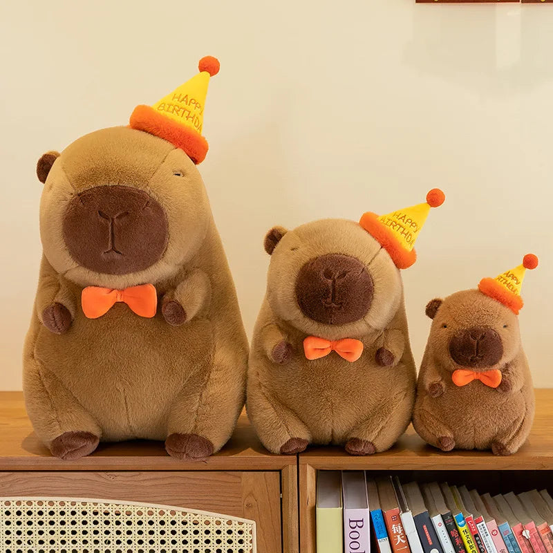 Three brown kawaii teddy bears with orange bow ties and party hats on a wooden surface.