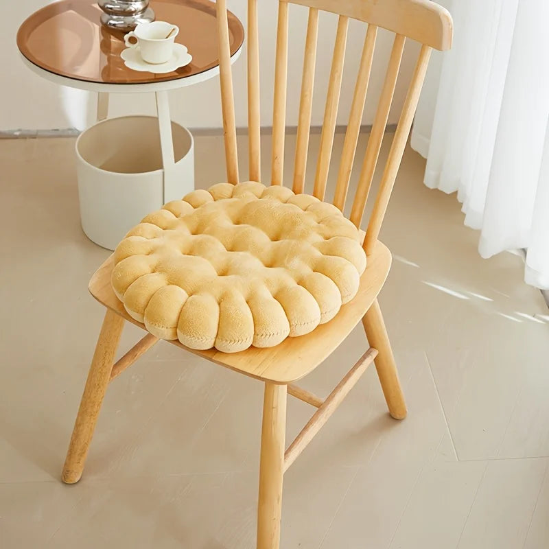 Wooden chair with a round yellow kawaii cushion on a light wooden floor.