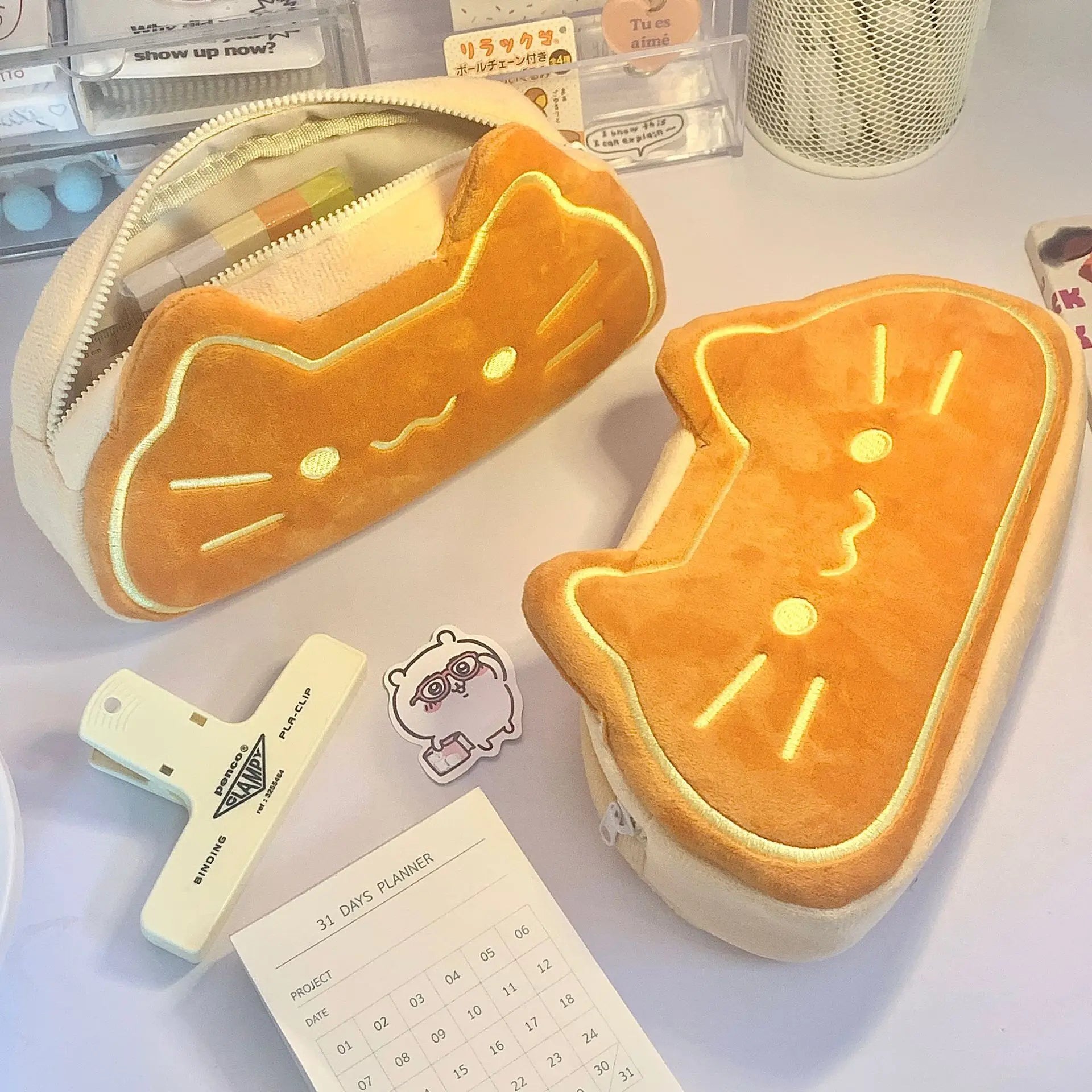 Two kawaii cartoon-style bread-shaped pouches on a desk with stationery items.