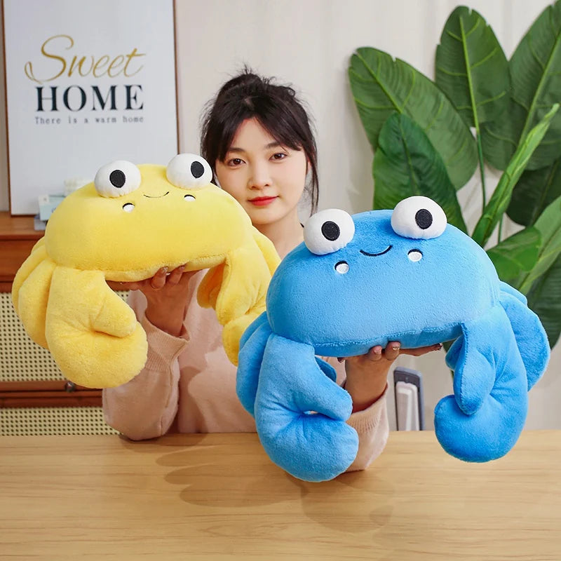 Person holding a yellow and a blue kawaii plush crab toy in a home setting.
