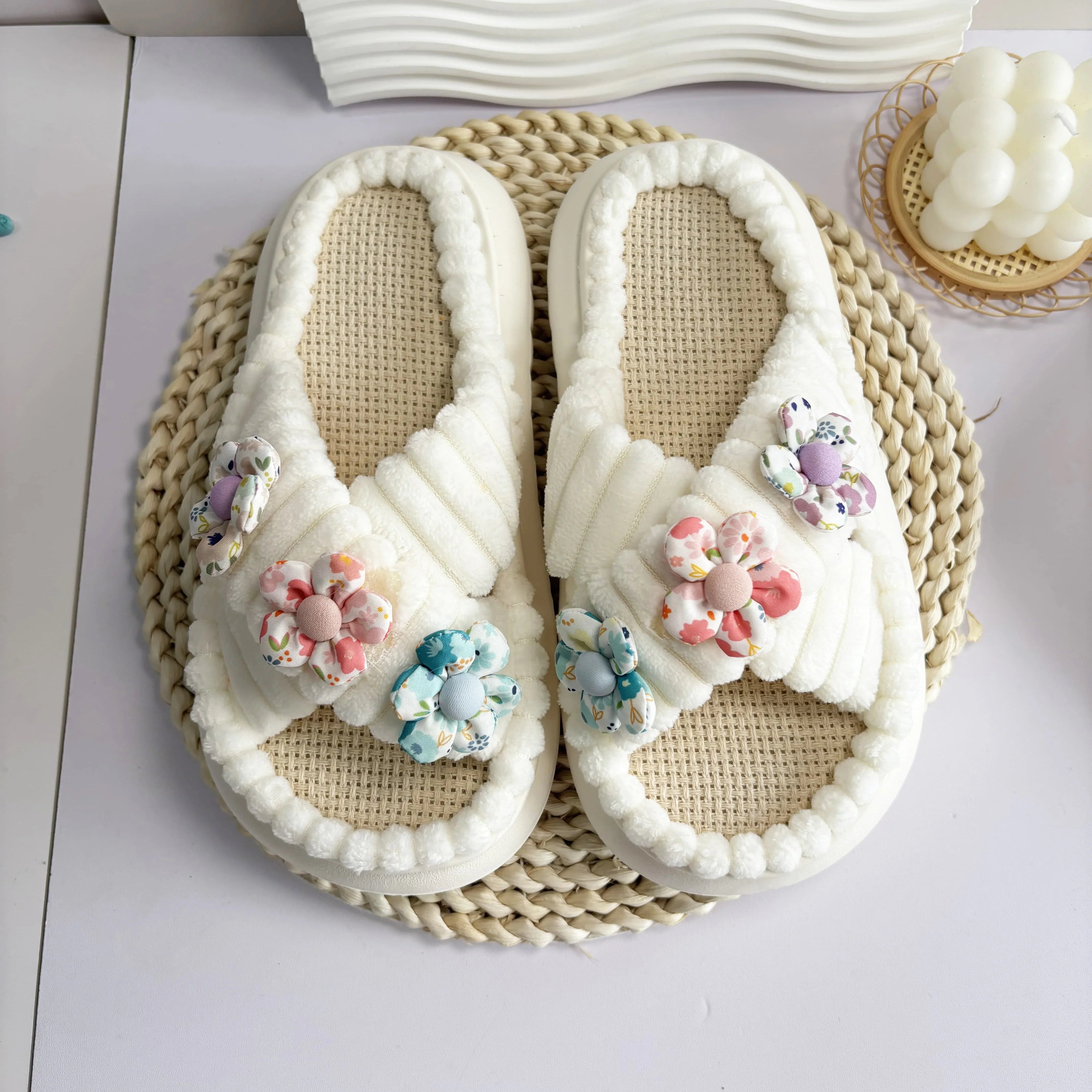 Pair of white kawaii slippers with floral decorations on a woven mat.