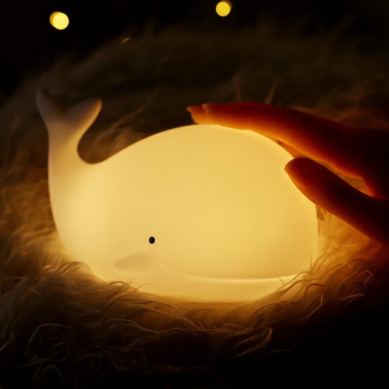 Hand holding a glowing moon-shaped kawaii night light with a cat in the background