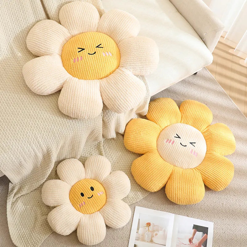 Three sunflower-shaped kawaii cushions with smiling faces on a soft surface.