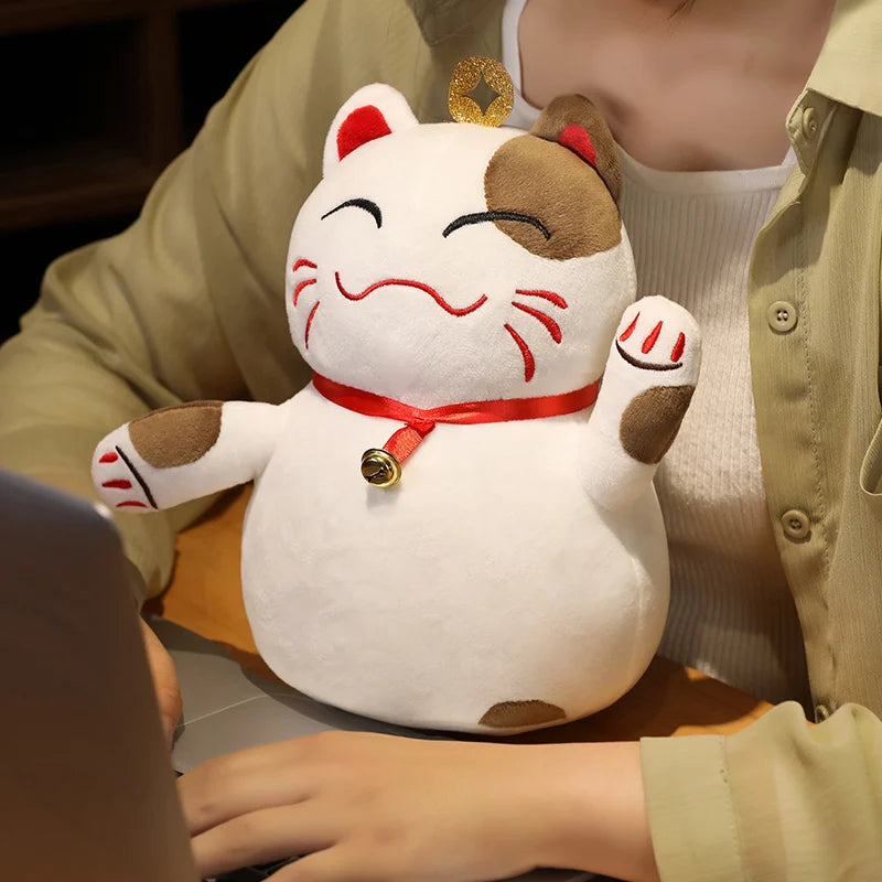 Kawaii plush toy cat with a red ribbon and bell on a person's lap
