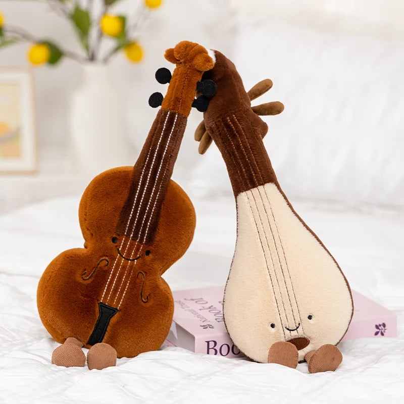 Two plush kawaii toys shaped like a violin and a lyre on a white surface with a blurred background.