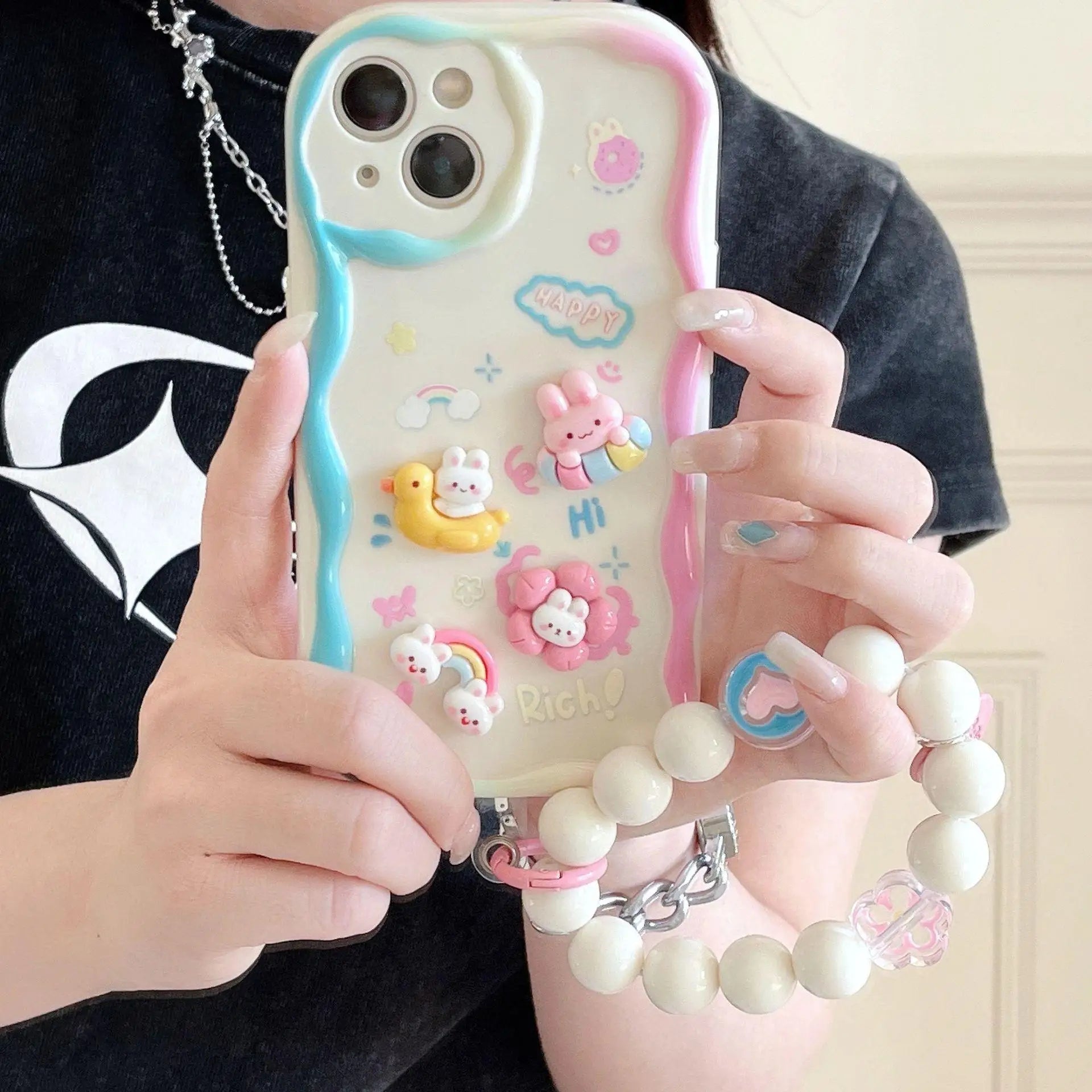 Person holding a phone case with kawaii cartoon designs and accessories.