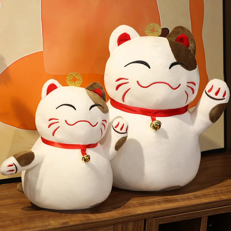 Two kawaii plush Maneki Neko cats on a wooden surface with a blurred background