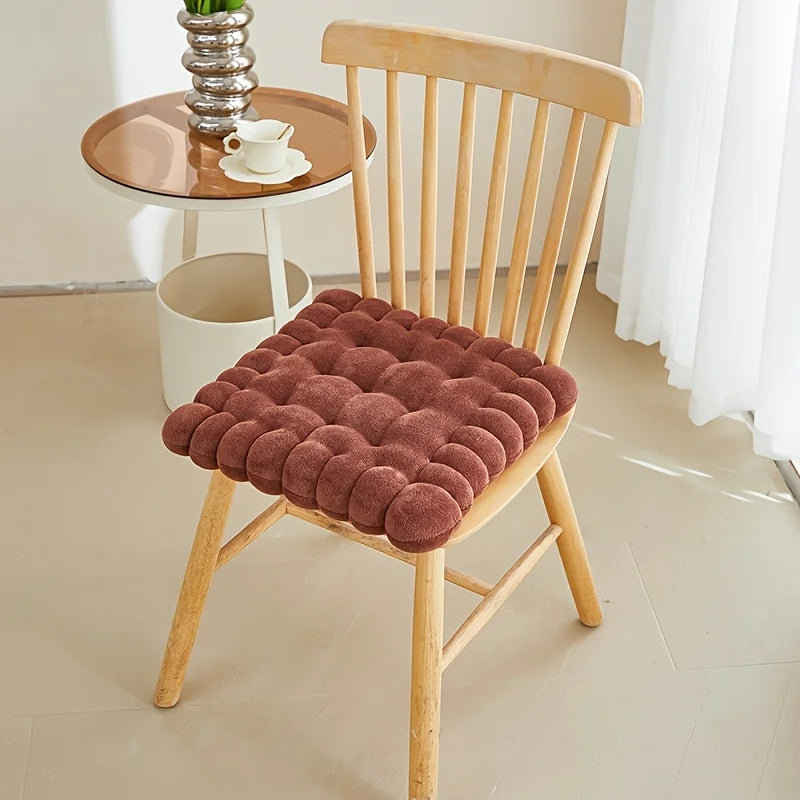 Brown kawaii cushion on a wooden chair with a small round table in the background