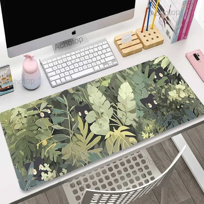 Desk setup with a green leafy desk mat featuring Kawaii black cat illustrations.