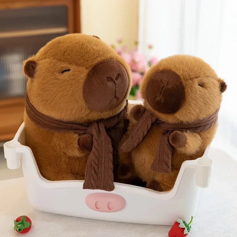 Two kawaii plush otters with scarves in a white container on a light surface.