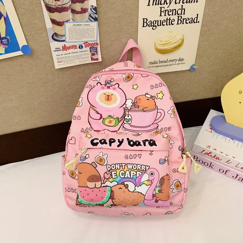Pink backpack with Kawaii cartoon characters on a table with vintage advertisements in the background