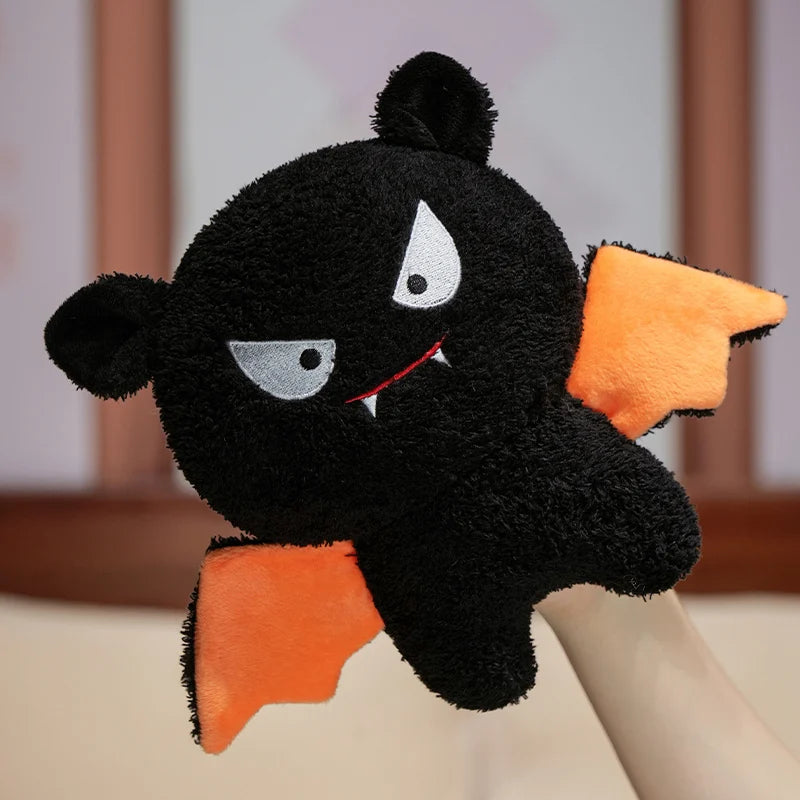 Black plush kawaii toy with orange wings on a neutral background