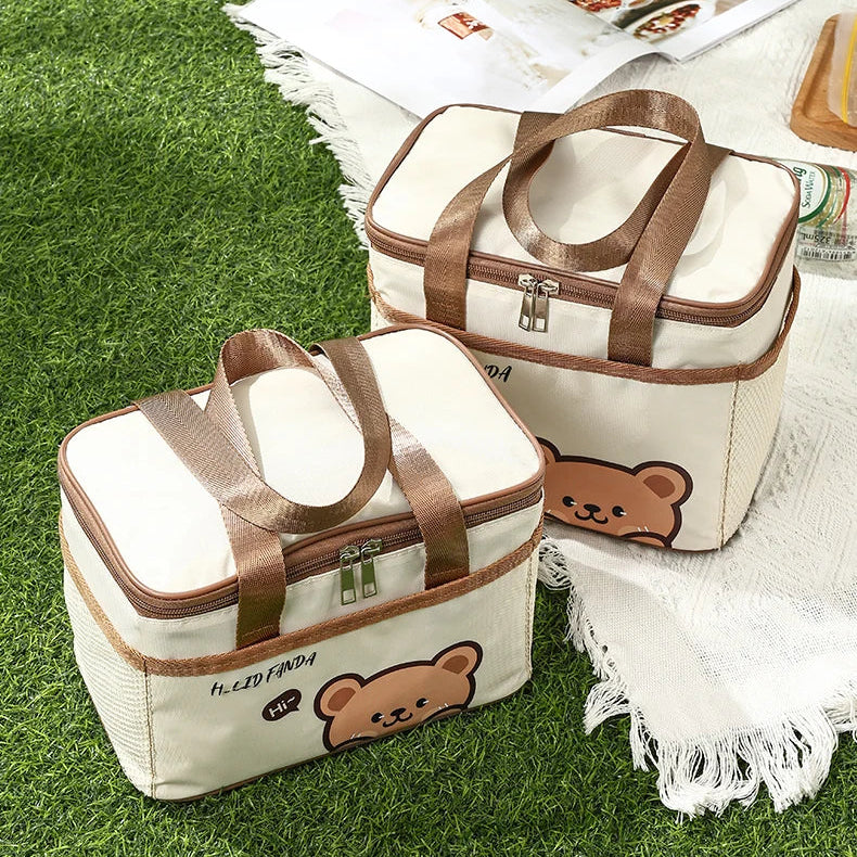 Two kawaii bear-themed bags on grass with a blanket underneath