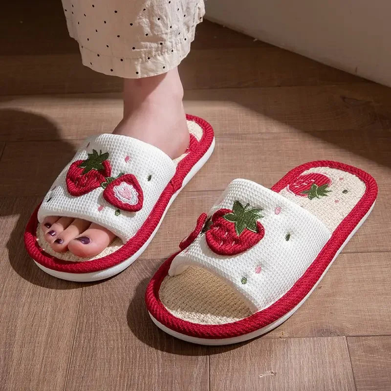 White slippers with red kawaii strawberry design on a wooden floor
