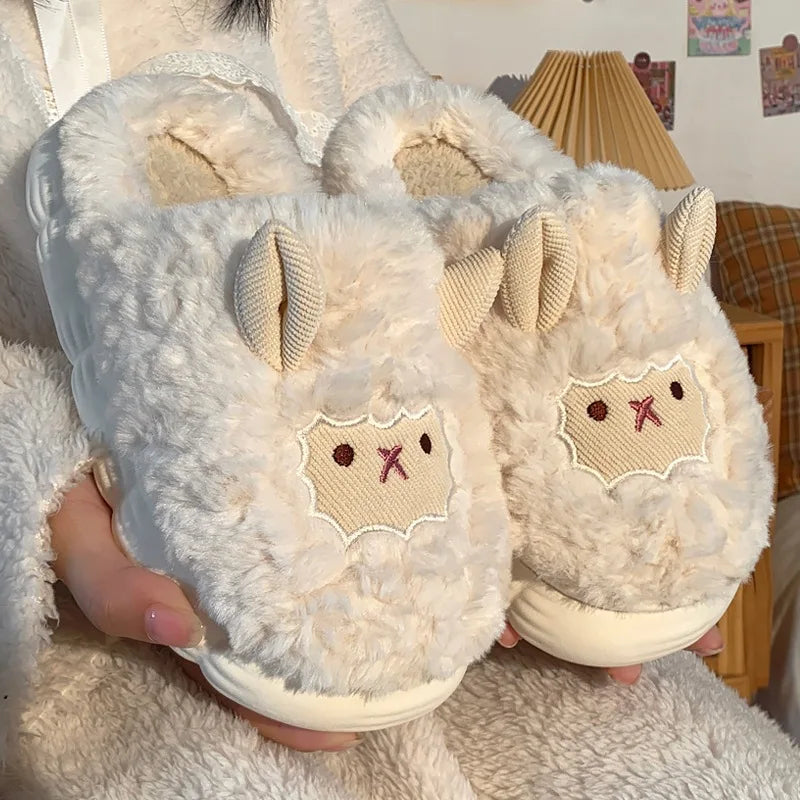 Pair of fluffy white slippers with kawaii cartoon face design held by a person.
