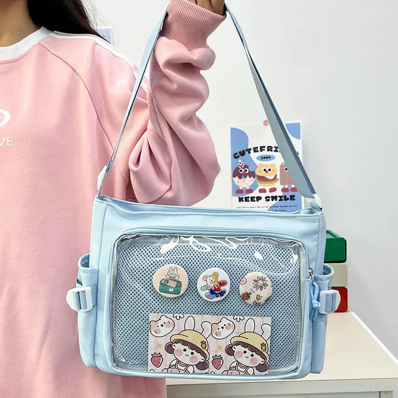 Light blue Kawaii crossbody bag with cartoon designs held by a person wearing a pink sweater.