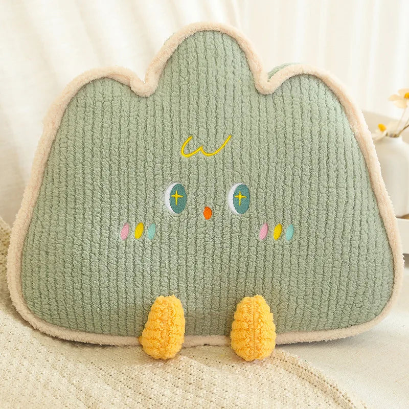 Green cloud-shaped kawaii pillow with embroidered face on a beige surface