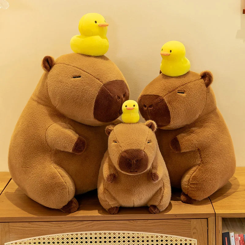 Three kawaii plush bears with yellow rubber ducks on their heads on a wooden surface.