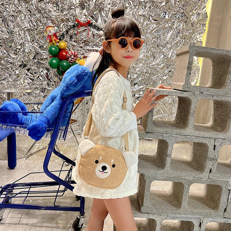 Woman holding a Kawaii teddy bear-shaped bag in an urban setting with a blue shopping cart and decorative wreath.