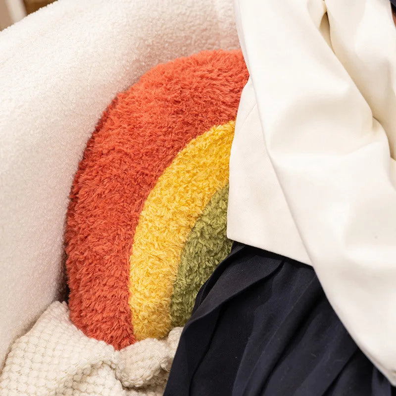 Round textured kawaii pillow with orange, yellow, and green stripes on a neutral background