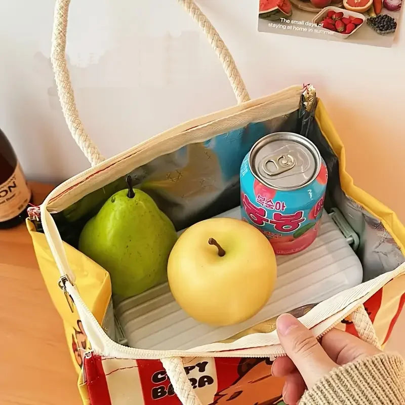 Open kawaii bag containing a pear, apple, and can of drink on a wooden surface.