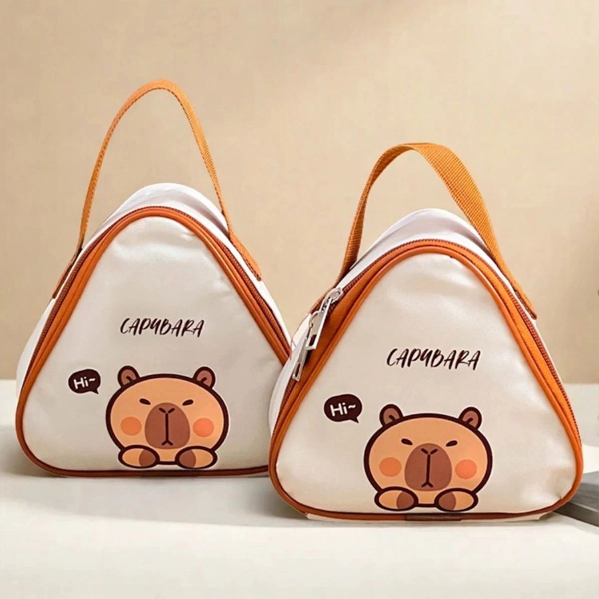 Two triangular bags with kawaii cartoon capybara design on a beige background