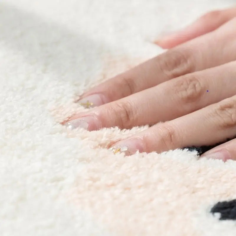 Close-up of a hand touching a soft, white textured kawaii rug