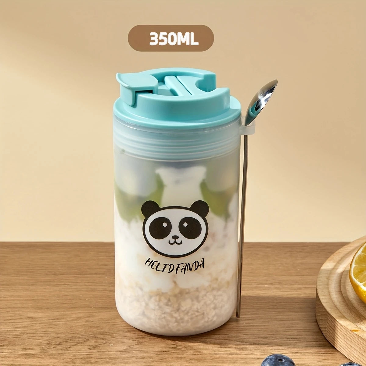 Clear tumbler with Kawaii panda design, blue lid, and straw on a wooden surface.