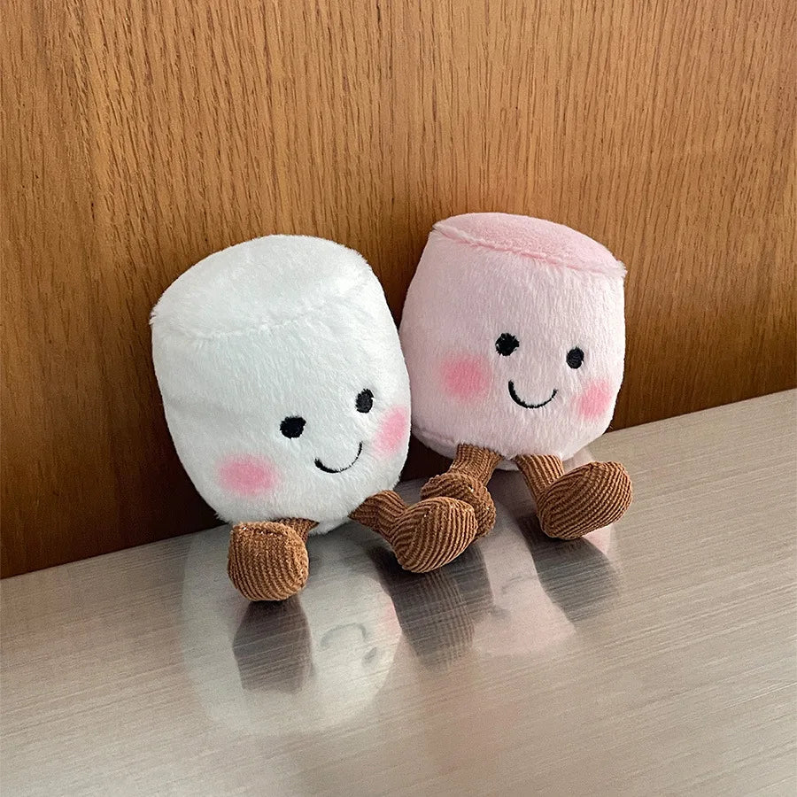 Two kawaii plush toys resembling marshmallows with smiling faces on a wooden surface.