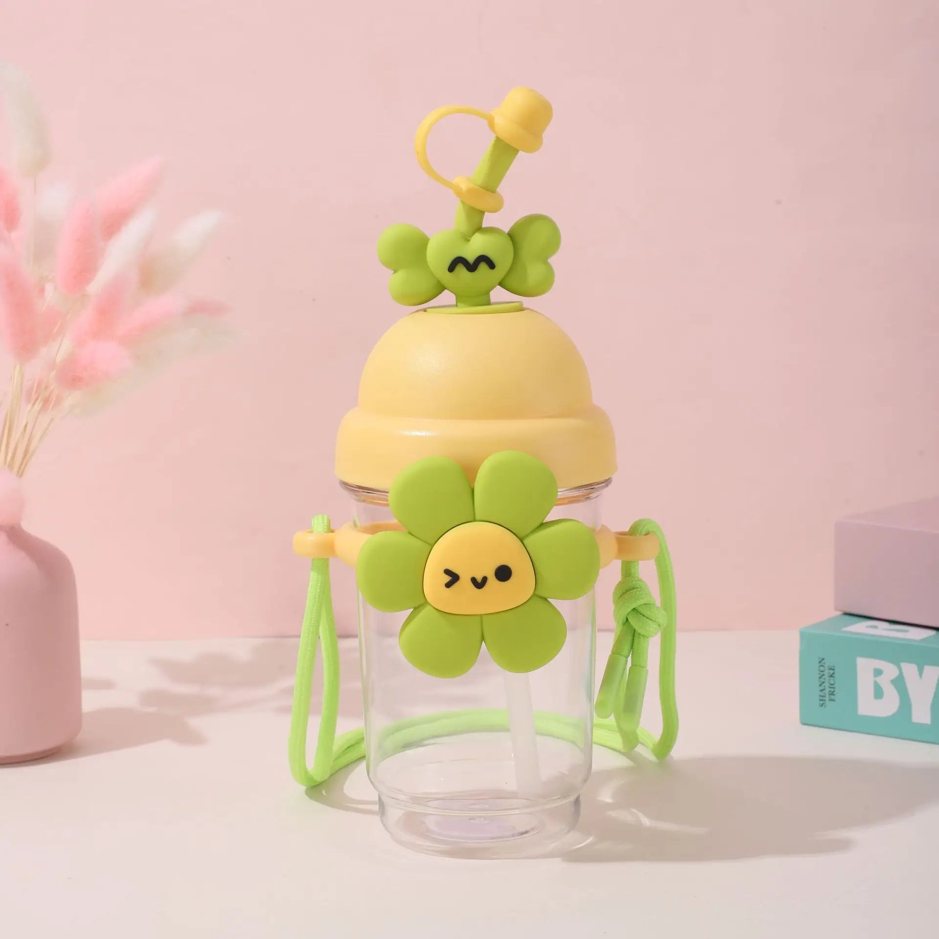 Children's Kawaii water bottle with green lid and handle on a pink background