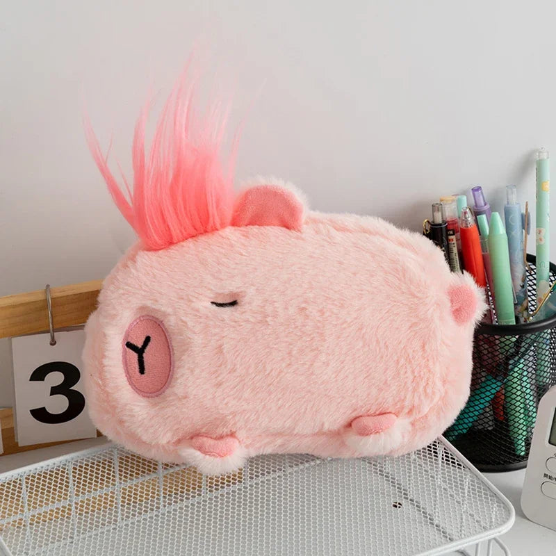 Pink kawaii plush toy resembling a creature with a mohawk on a desk with stationery items.