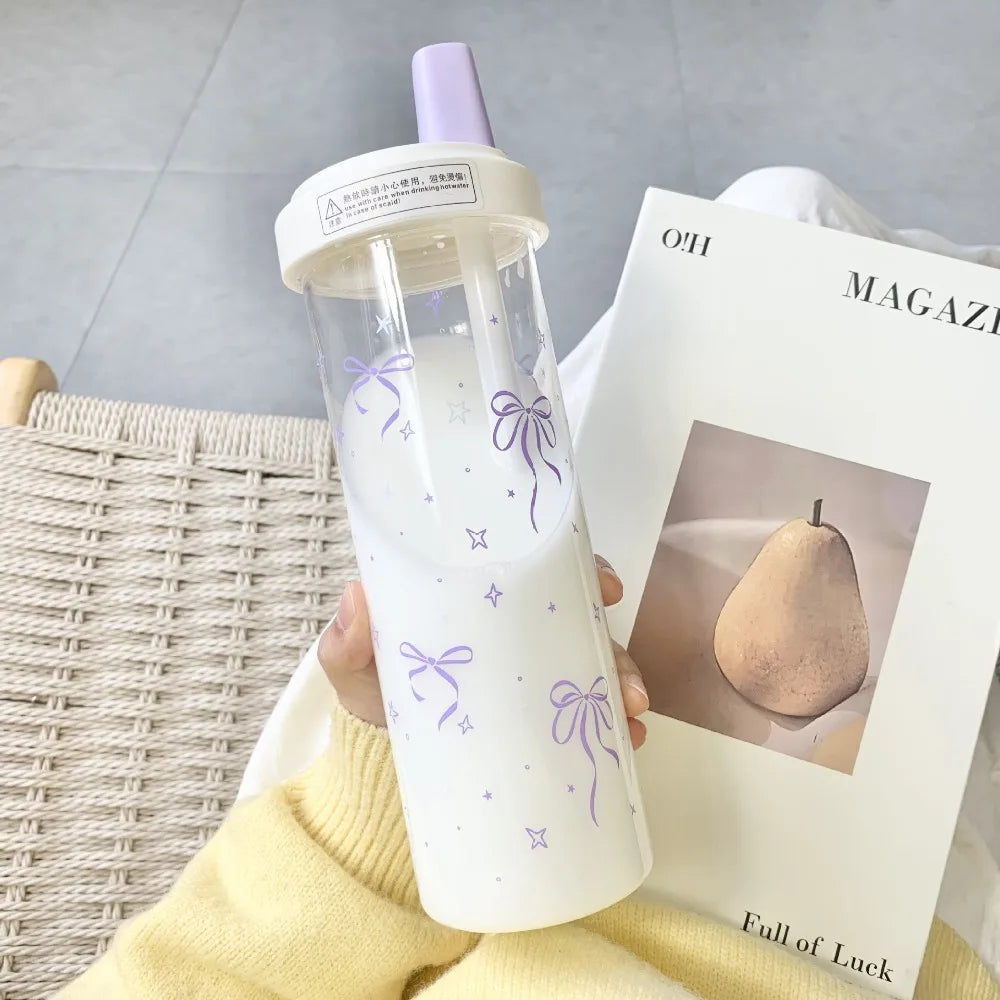 Kawaii clear bottle with purple accents held by a person, with a magazine featuring a pear on a light gray background.