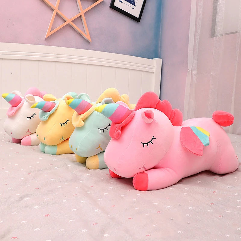 Set of colorful unicorn kawaii plush toys on a bed with a light purple wall in the background.