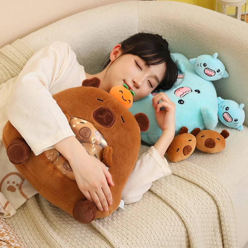 Person holding a brown kawaii plush toy with a smiley face, surrounded by more plush toys on a beige couch.
