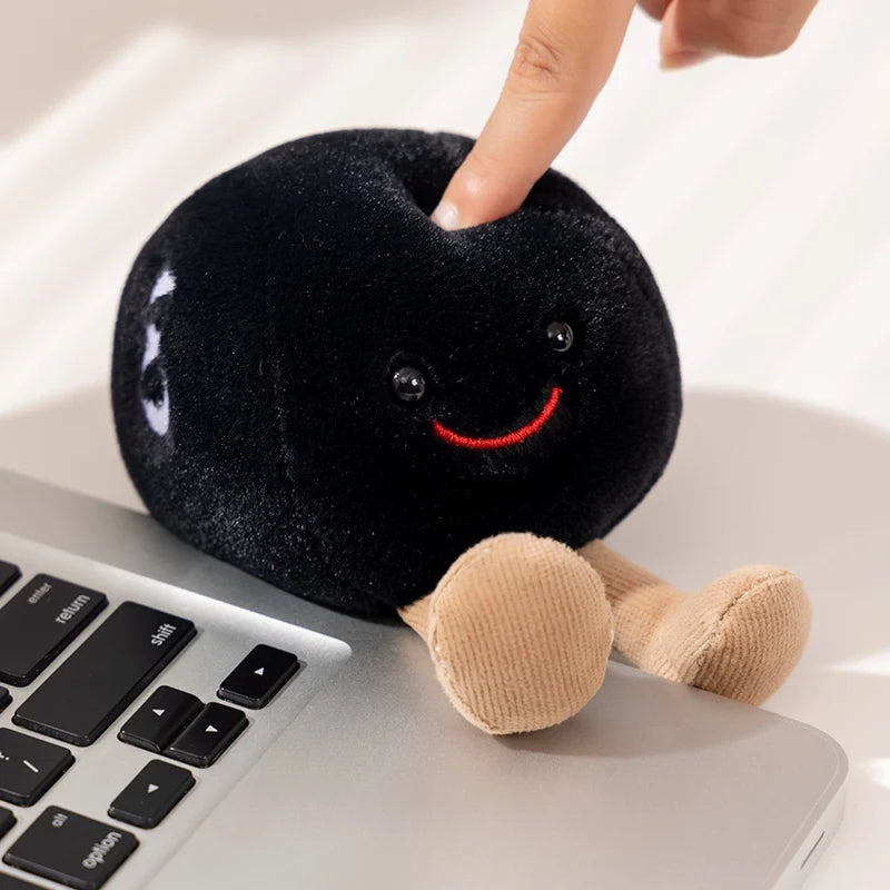 Plush kawaii toy resembling a blackberry with a smiling face on a laptop