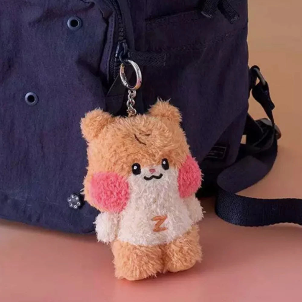Plush kawaii keychain with a bear design attached to a blue backpack on a beige surface