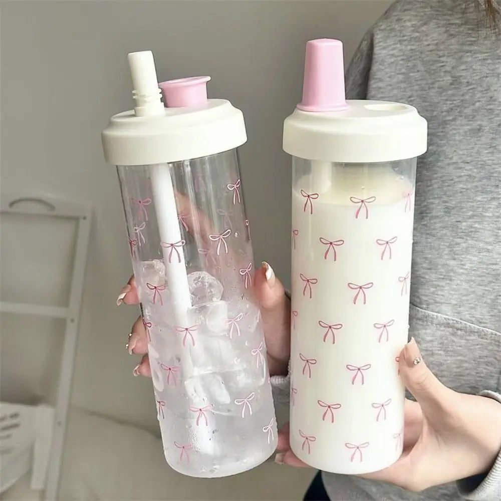 Two Kawaii sippy cups with pink lids and bow patterns held by a person.